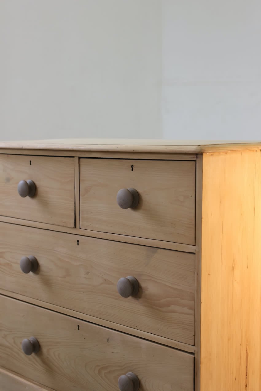 classic english deep four drawer antique pine chest completey restored standing on a plinth with new knobs.