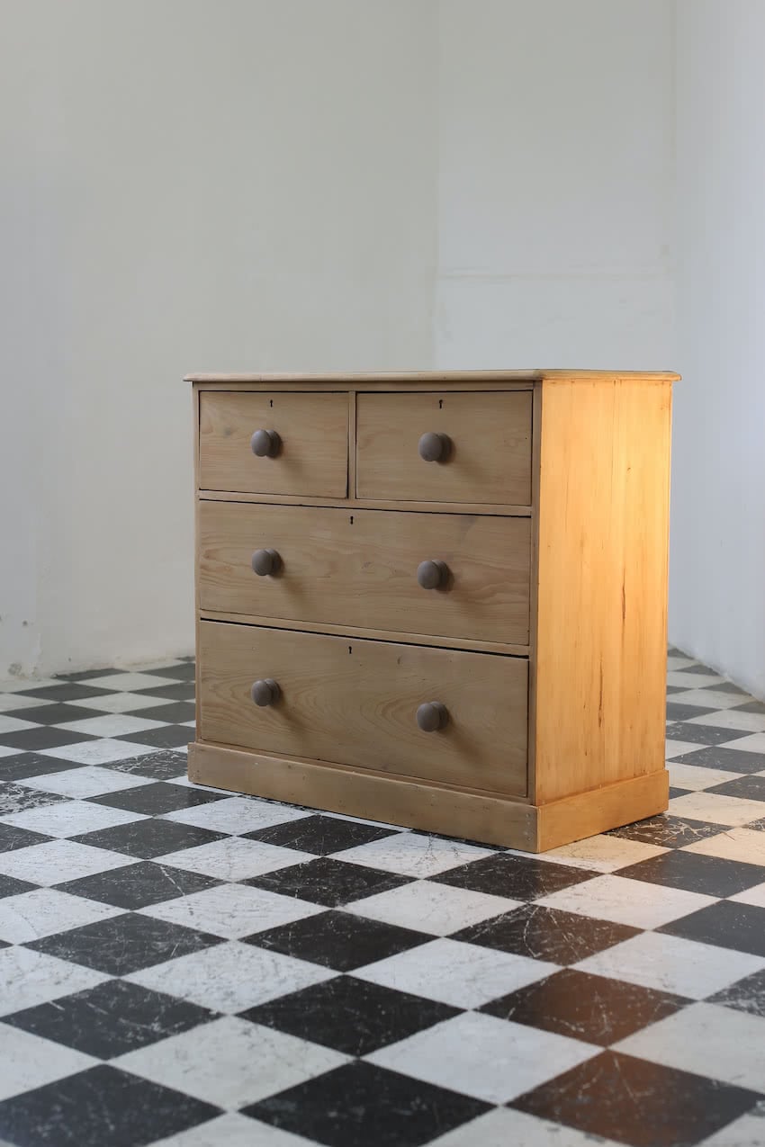 classic english deep four drawer antique pine chest completey restored standing on a plinth with new knobs.