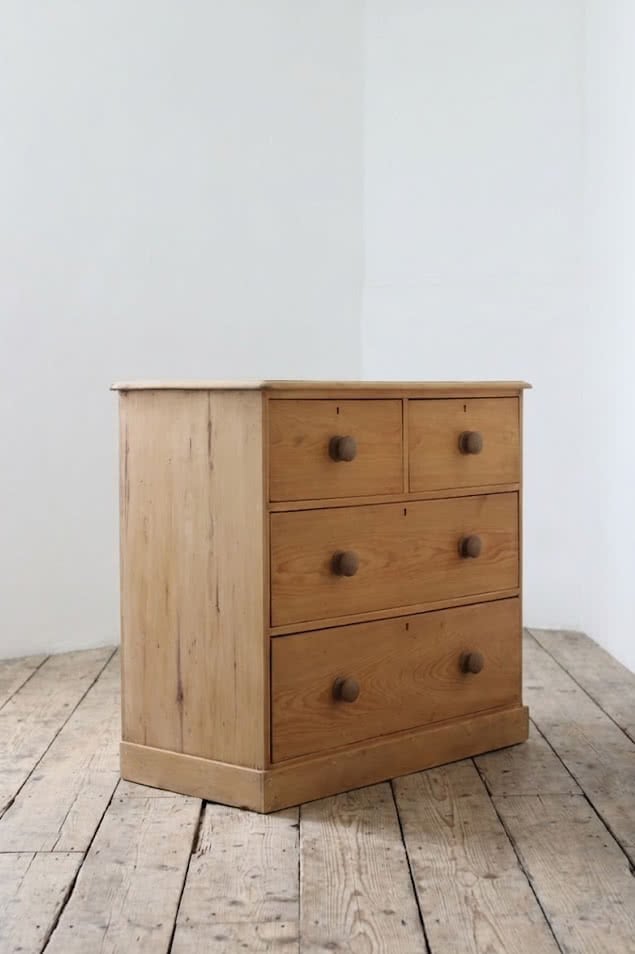classic english deep four drawer antique pine chest completey restored standing on a plinth with new knobs.