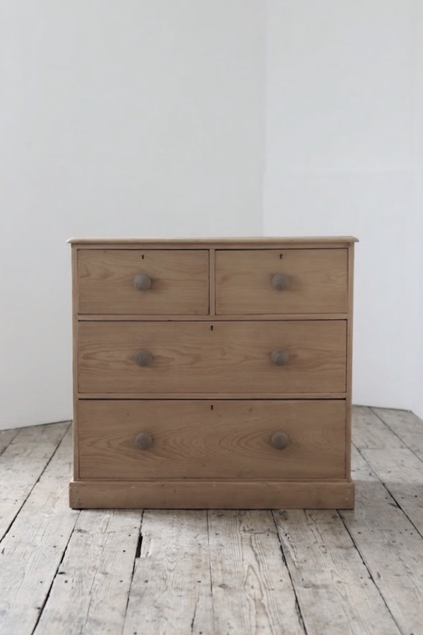 classic english deep four drawer antique pine chest completey restored standing on a plinth with new knobs.