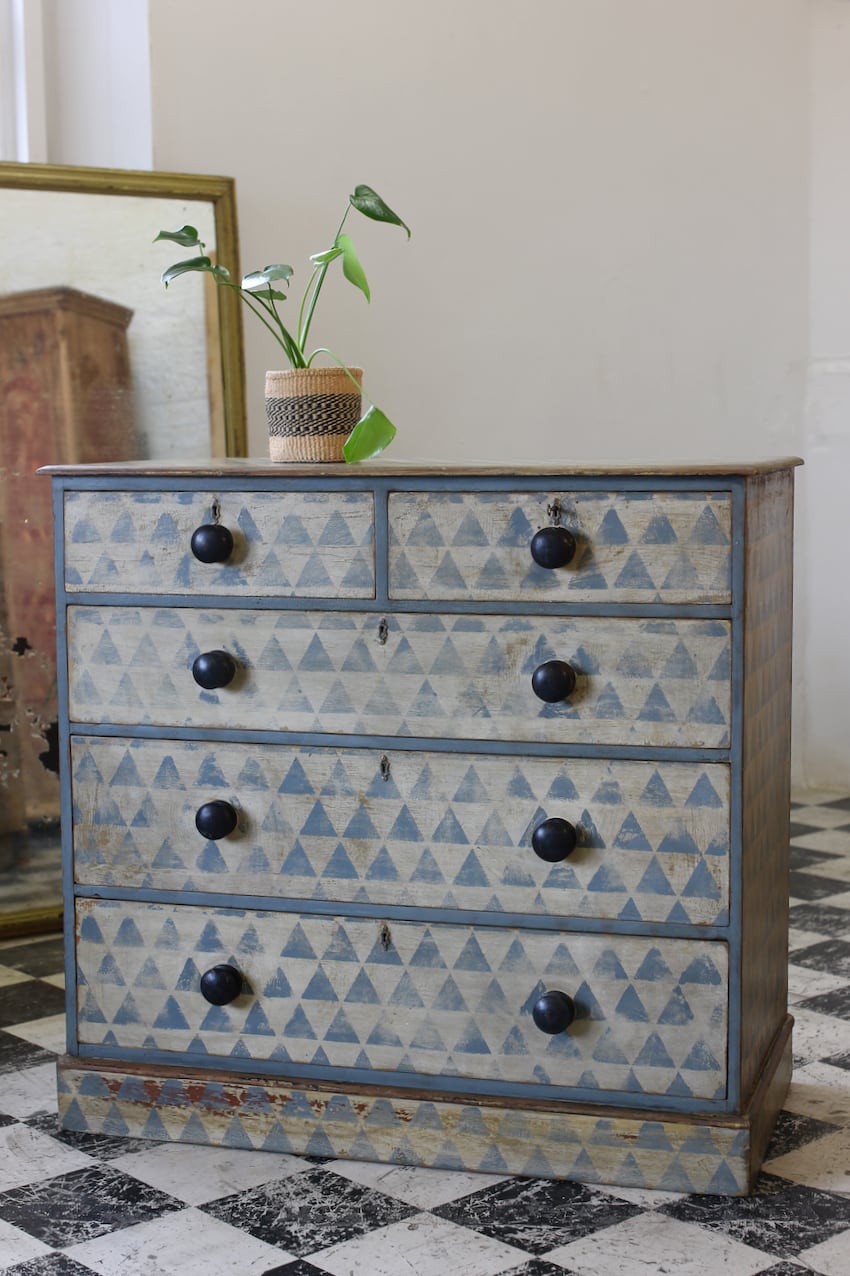 beautiful geometric antique restored chest in original paint with later hand painted pattern, silver shaped escutcheons, black original knobs & sits on a plinth.