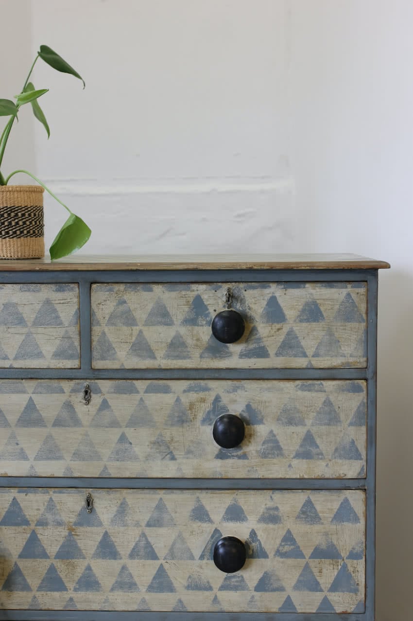 beautiful geometric antique restored chest in original paint with later hand painted pattern, silver shaped escutcheons, black original knobs & sits on a plinth.