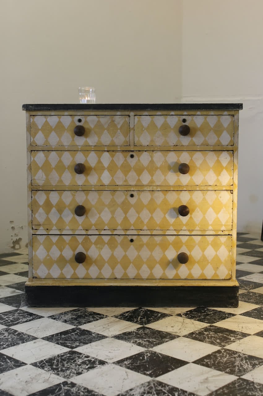 fabulous antique pine chest with lemon & white geometric diamond pattern, contrasting wooden knobs & black plinth.
