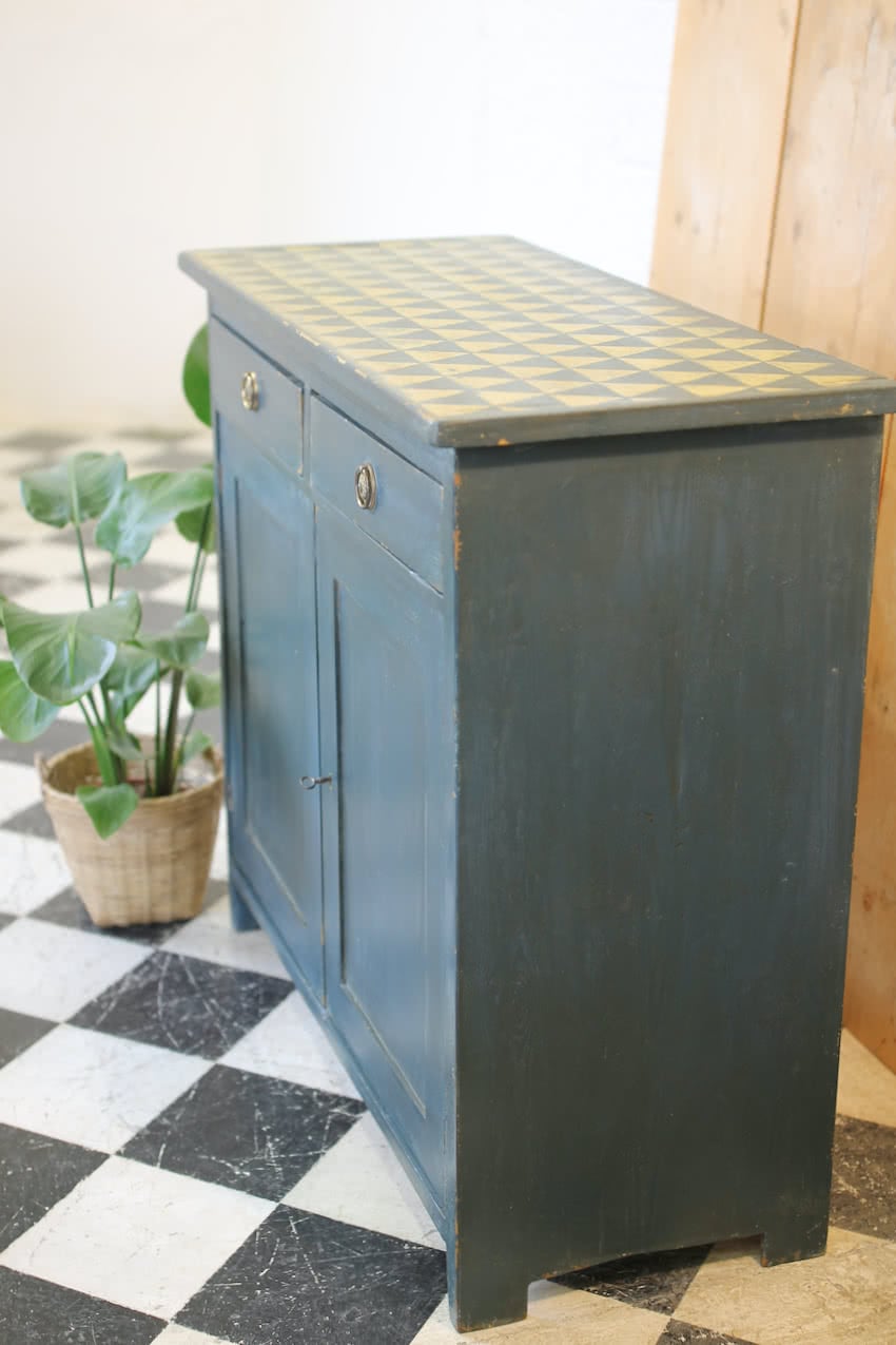 blue painted pine cupboard with two drawers with a shelf, a geometric patterned top & interior doors and drawers painted in Lichen. 
