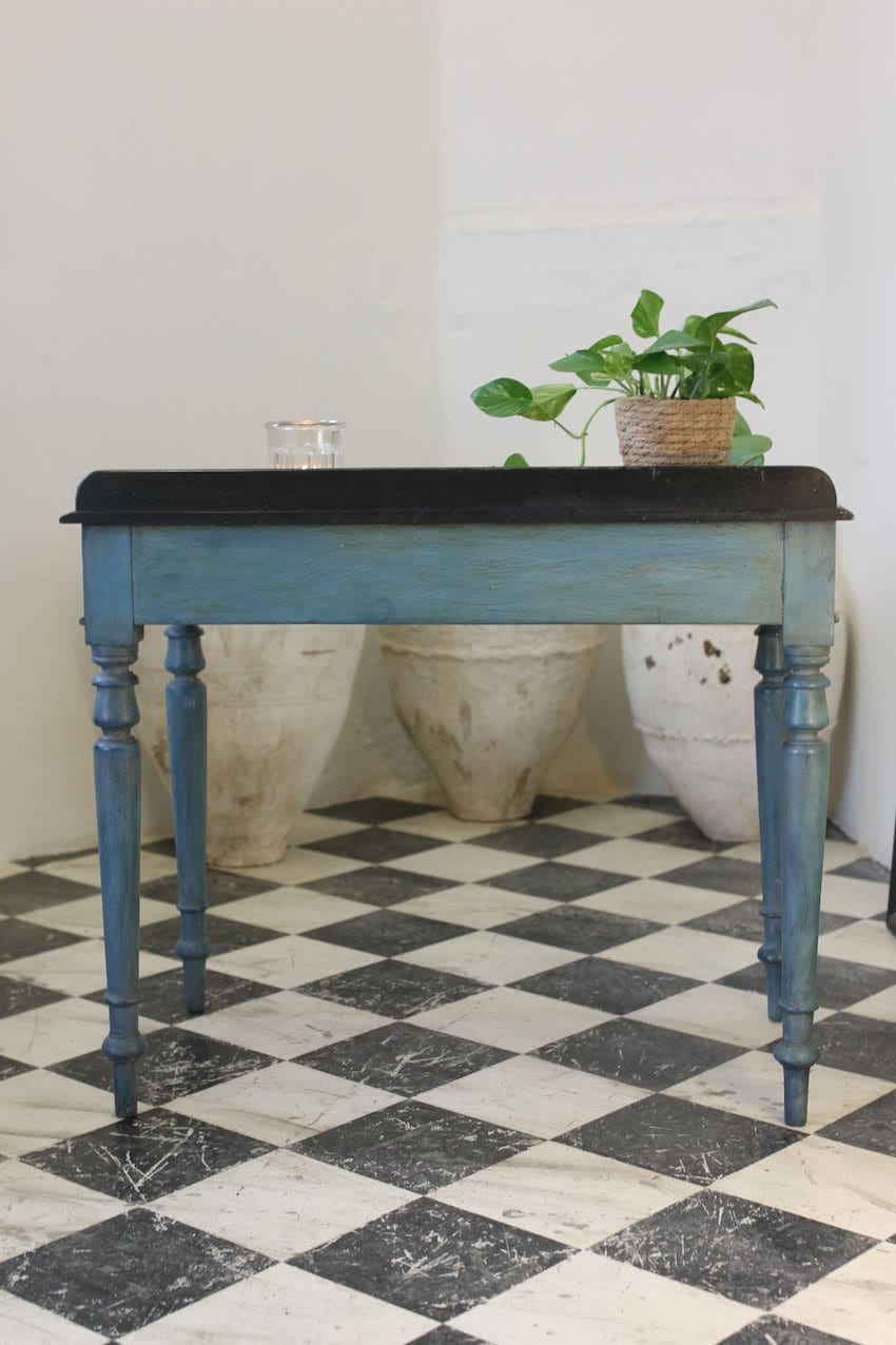 pretty two drawer side table refinished in blue, the table has a black top, small wooden knobs and elegant turned feet, it also has a waxed finsh.